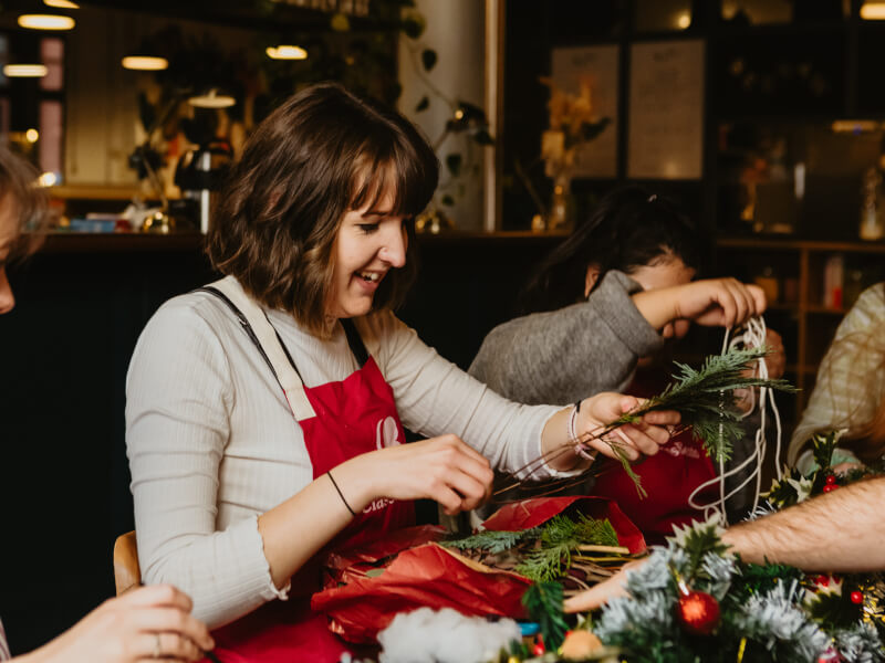 Woman in red apron making a Christmas wreath